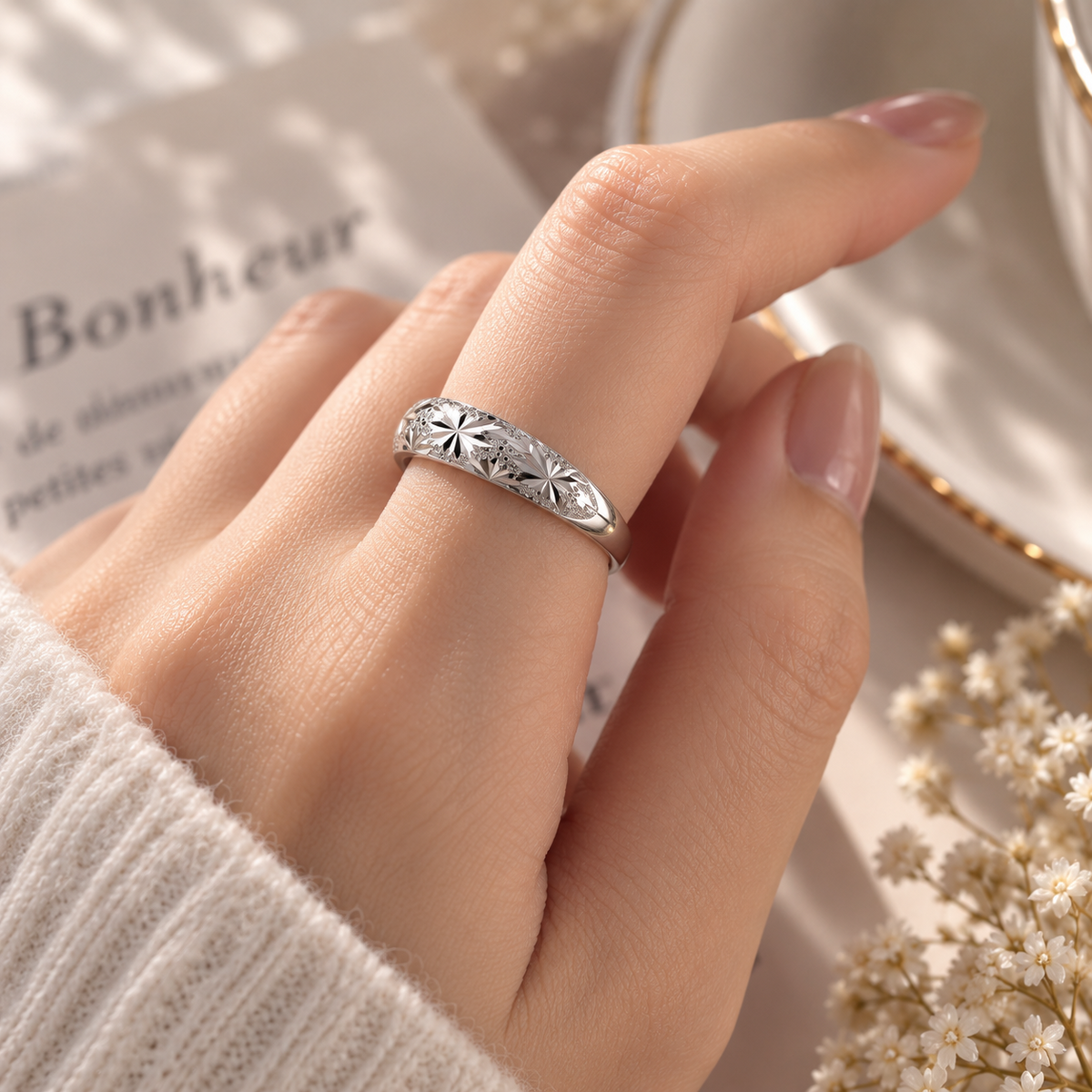 Bague argentée à motif floral portée au doigt, vue du décor et des proportions