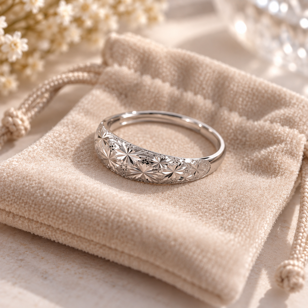 Bague ajustable argentée à motif floral présentée sur un pochon en velours beige