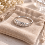 Bague ajustable argentée à motif floral présentée sur un pochon en velours beige