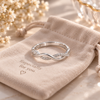 Bague argentée entrelacée présentée sur un pochon en velours beige
