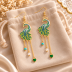 Boucles d’oreilles paon à pendentifs présentées sur une pochette en velours