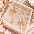 Boucles d’oreilles éventails fleuris dorés présentées sur une pochette