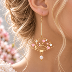 Boucle d’oreille portée avec tige dorée au-dessus de l’éventail floral
