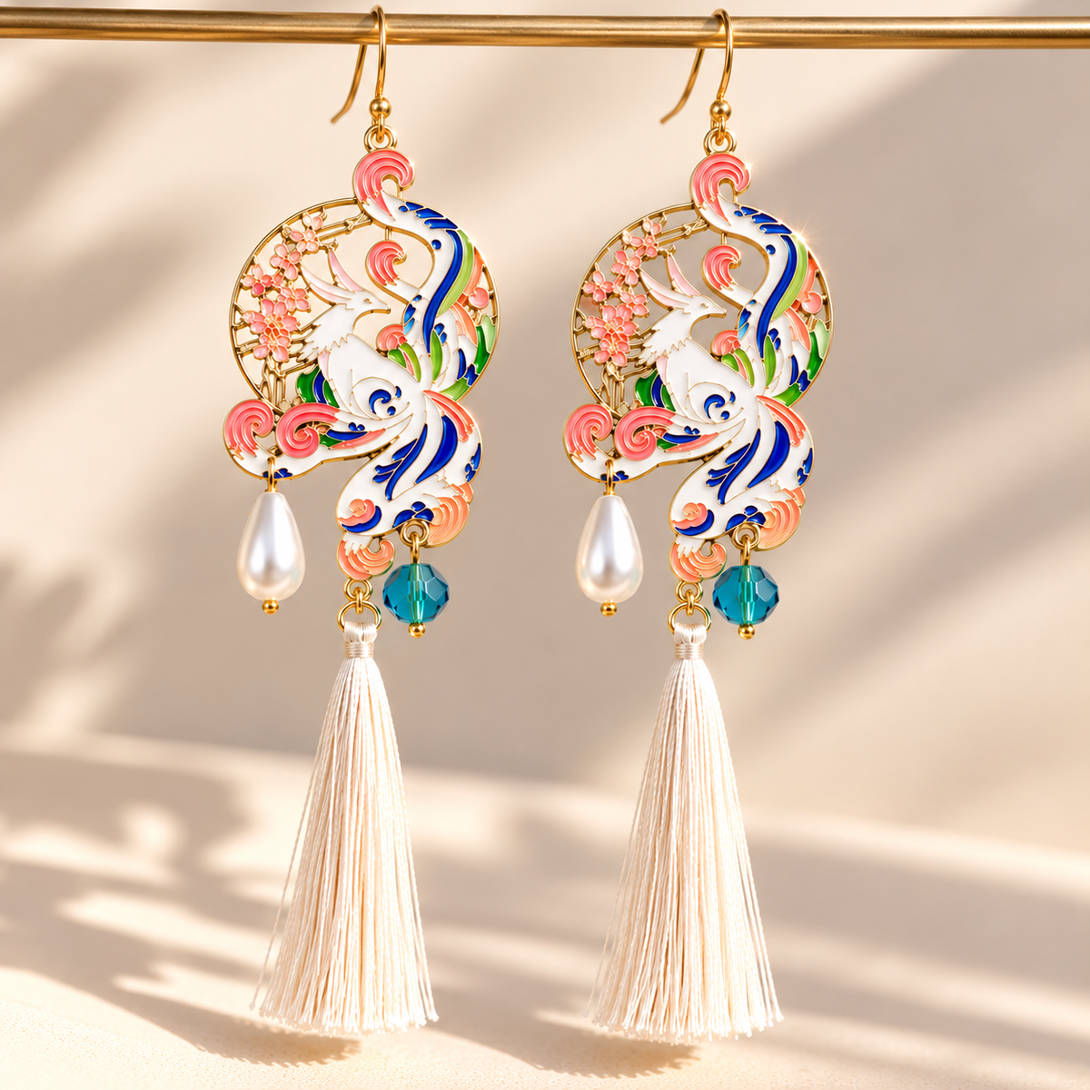 Paire de boucles d’oreilles phénix multicolores, finition dorée et longs pompons blancs