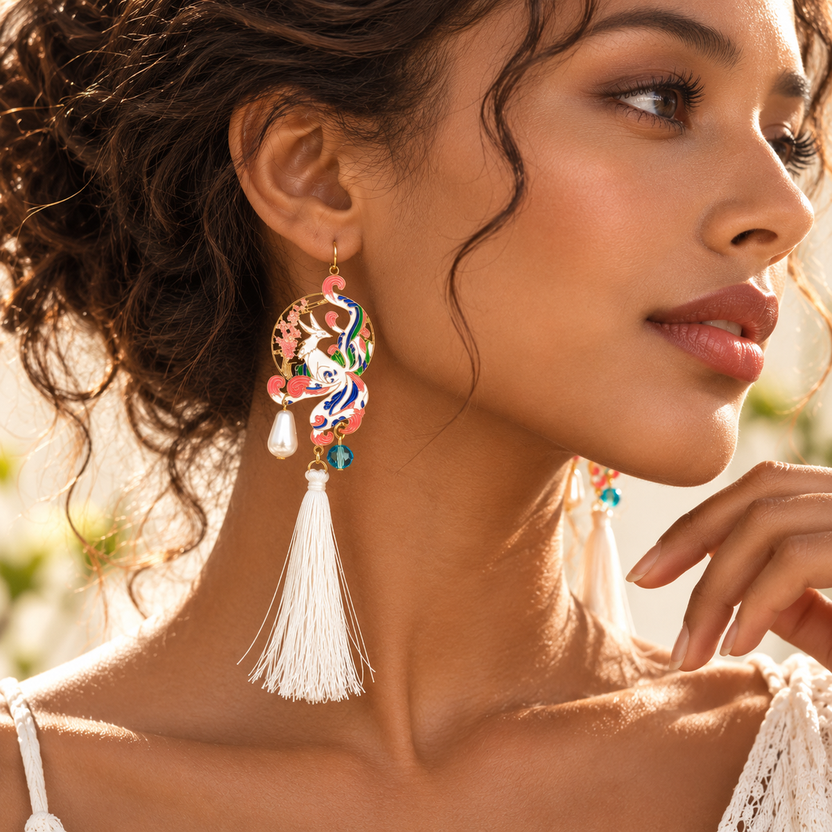 Boucle d’oreille phénix à pompon blanc portée, motifs roses, bleus et verts