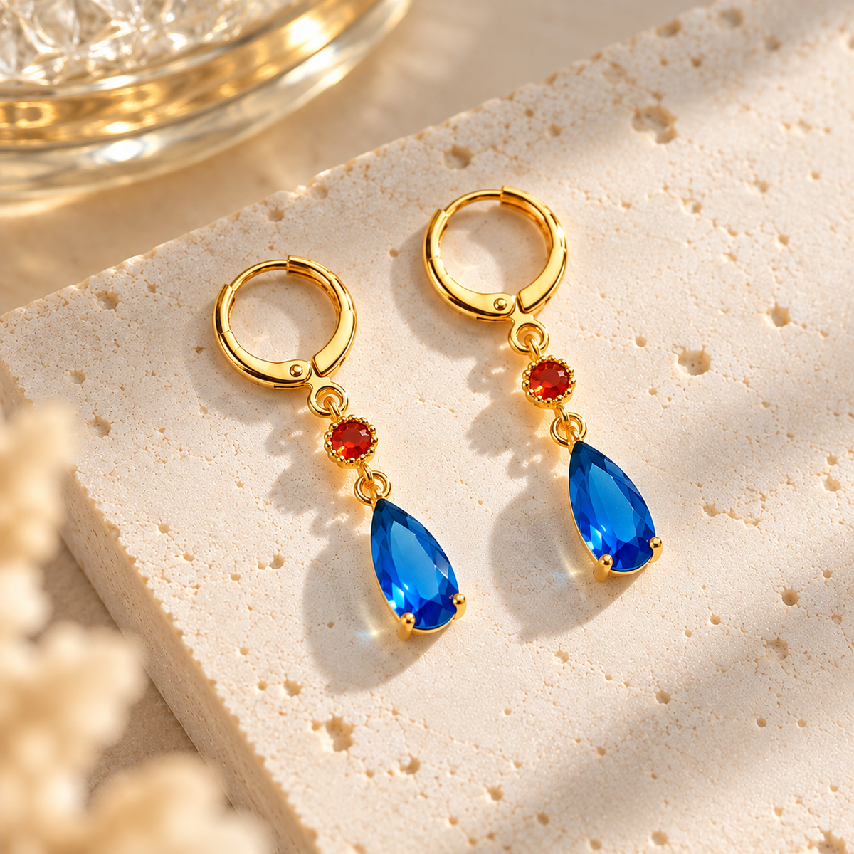 Paire de boucles d’oreilles dorées bleues et rouges posées à plat