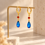 Paire de boucles d’oreilles dorées bleues et rouges sur présentoir