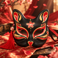 Masque de renard kitsune noir, rouge et doré vu de face avec pompon rouge
